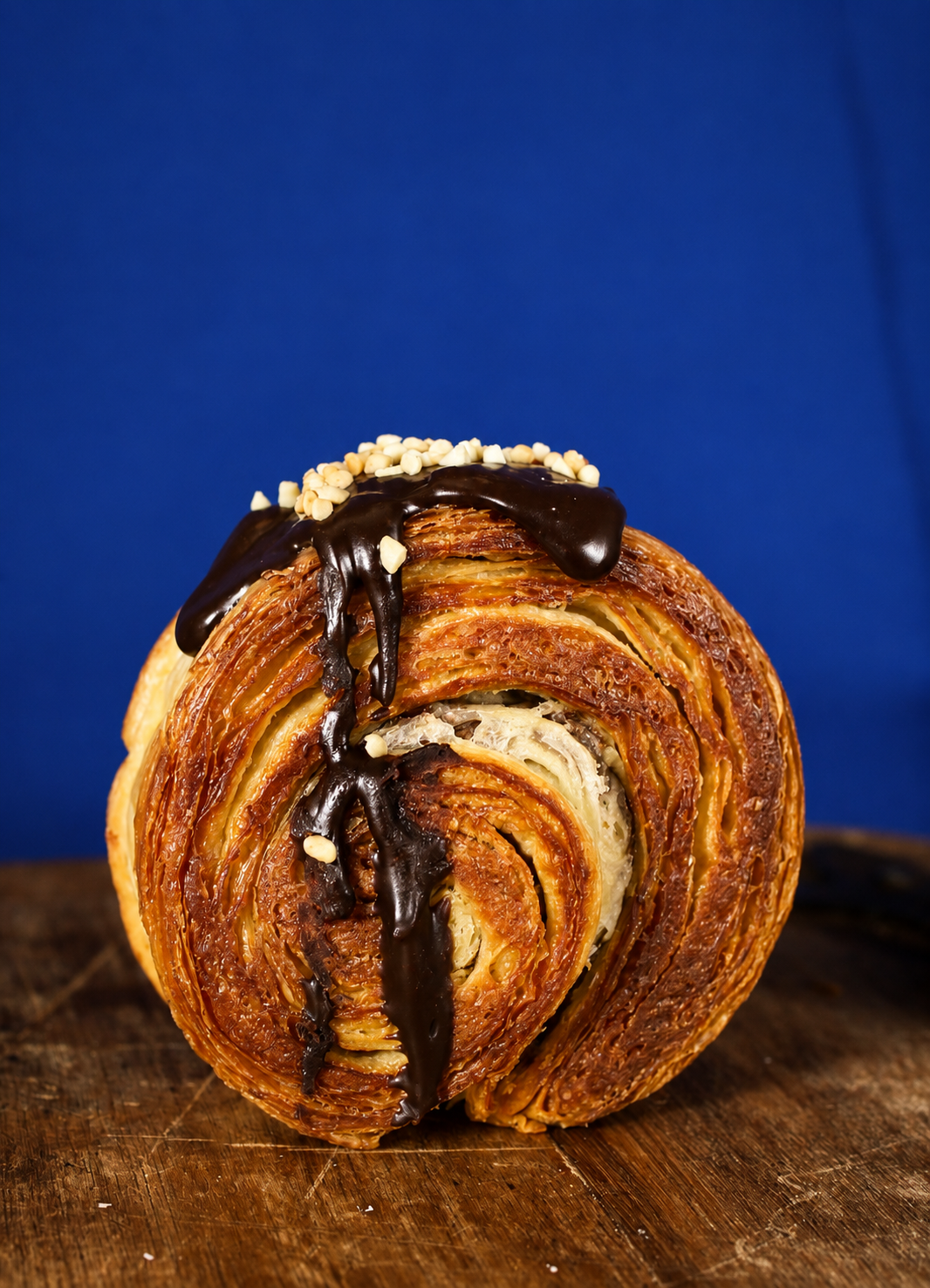 Nutella filled circular croissant with glossy chocolate drizzle flowing down sides | Dough Couture